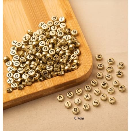 Miçangas douradas com letras pretas 15g ou 30g