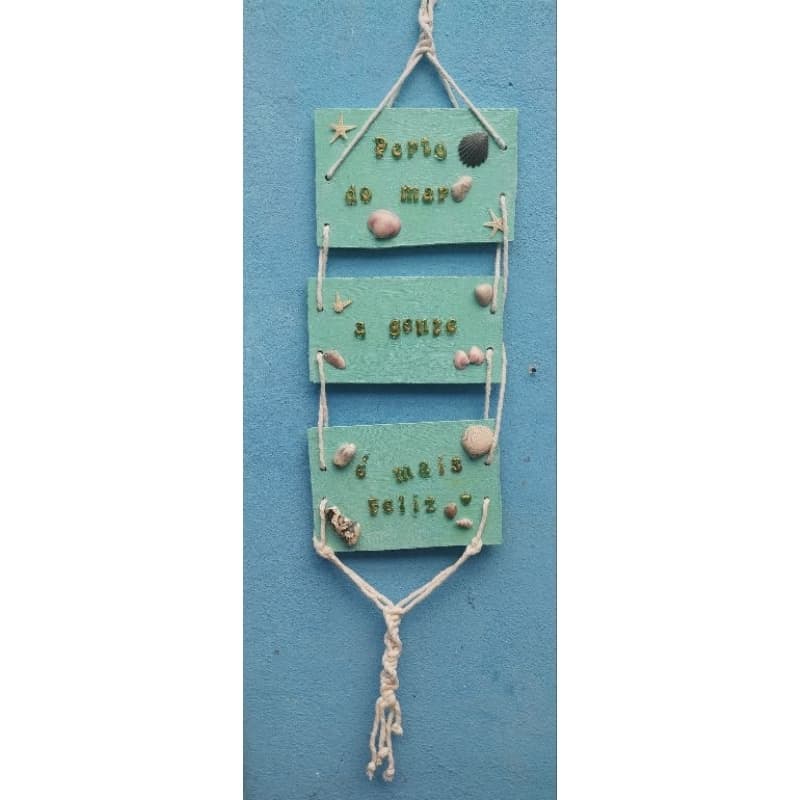 Placa decorativa marítima com frase feita de resina: "Perto do mar a gente é mais feliz"