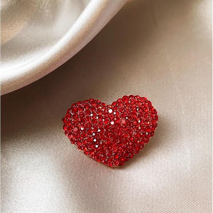 Broche de coração vermelho cravejado de diamantes para fixar acessórios de vestuário.