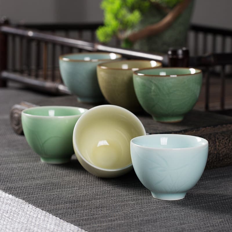 Xícara de chá Kongshan Xinyu Longquan de celadon com esmalte craquelado do forno Di Ge e pequena escultura de orquídea,