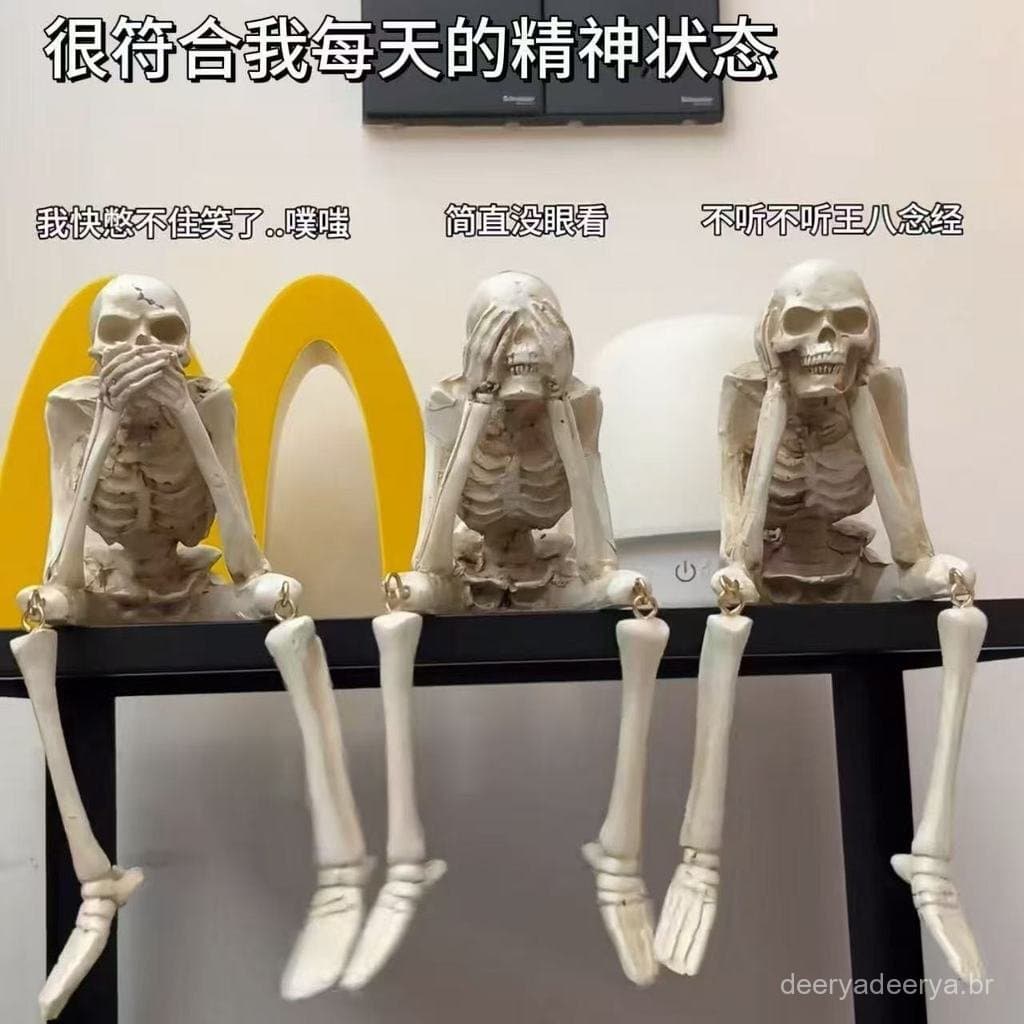 Ornamento de caveira com pernas penduradas e membros inferiores móveis, não ouve, vê nem fala, uma decoração de mesa div