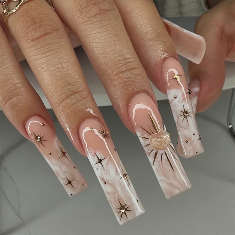 Unhas postiças longas estilo francês com efeito degradê e padrão de estrelas e corações.