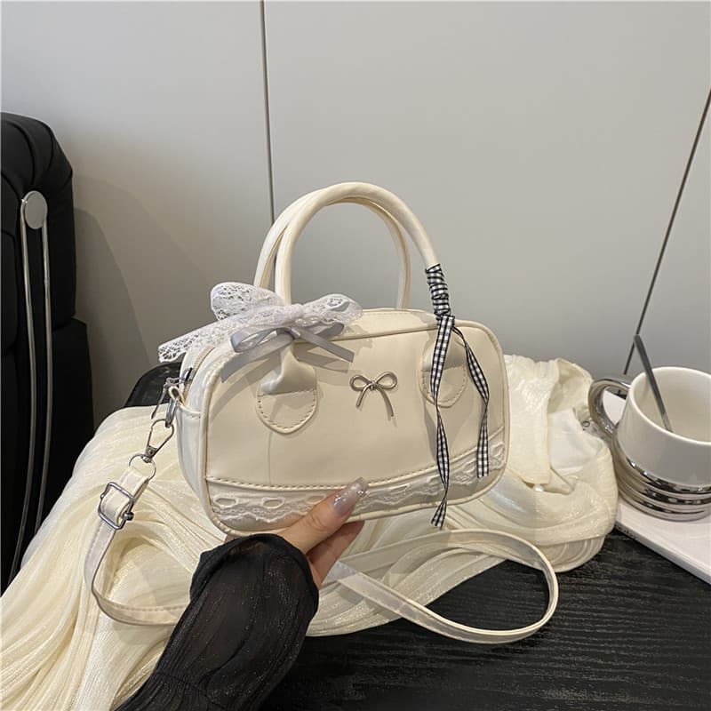 A versão coreana da bolsa apresenta um delicado laço de renda e metal, típico deste estilo.