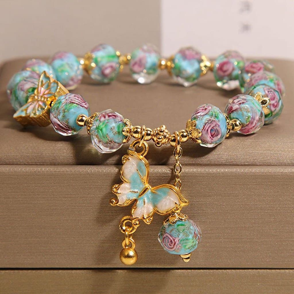 Pulseira de contas de vidro rosa estilo boho com pingente de borboleta azul, feita à mão com efeito de gotejamento.   BU