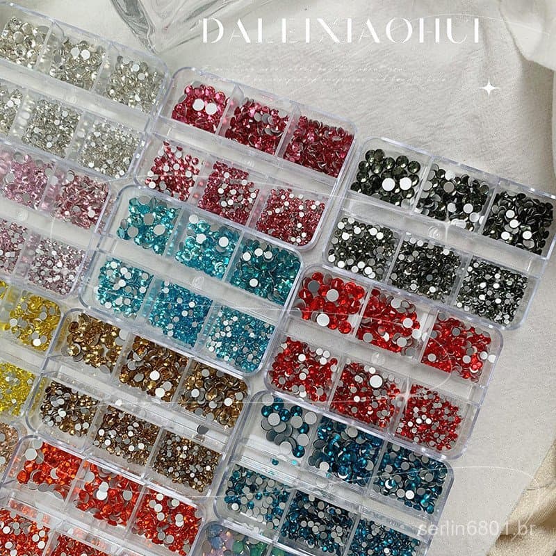 Strass para decoração de unhas de tamanhos variados em uma caixa de fundo plano, pequenos acessórios brilhantes, caixa d
