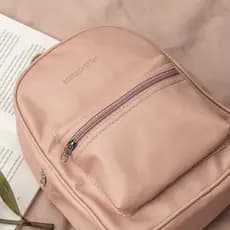 Mochila feminina casual, pequena, com bolso na frente e em couro sintético nas cores preto, nude, caramelo e marrom