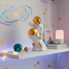 Astronauta em resina no foguete branco e dourado